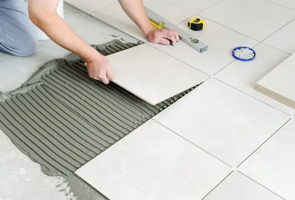 Professional tile installer placing ceramic tiles with mortar for a clean and durable floor by Jorge Carpentry & Tile Services.