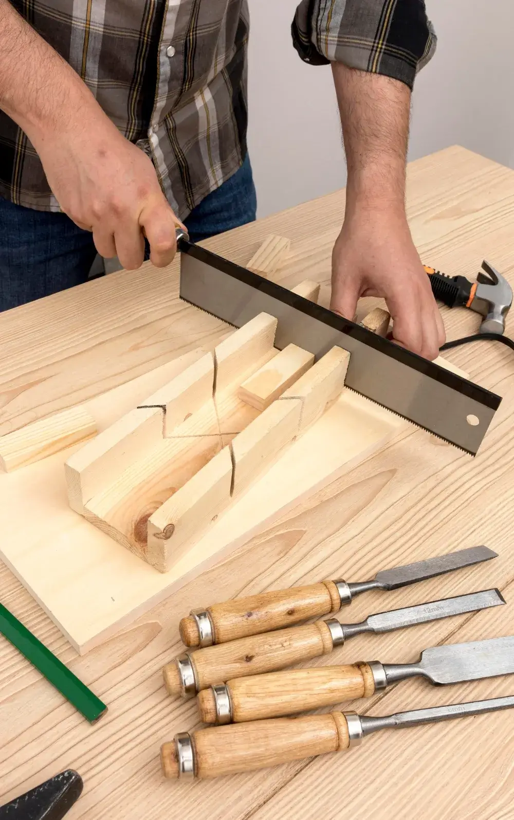 Hand sawing wood using a miter box with chisels on a workbench – Jorge Carpentry & Tile Services.