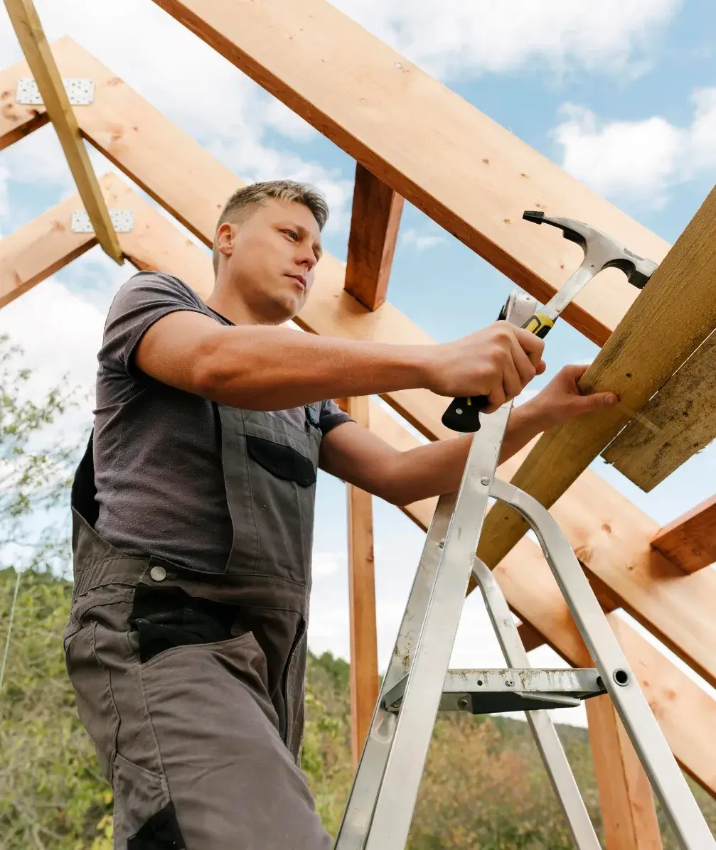 Carpenter installing wood beams on a roof frame using a hammer – Jorge Carpentry & Tile Services