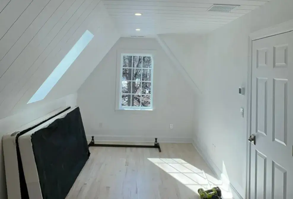 Bright attic room with wood flooring and custom ceiling finish