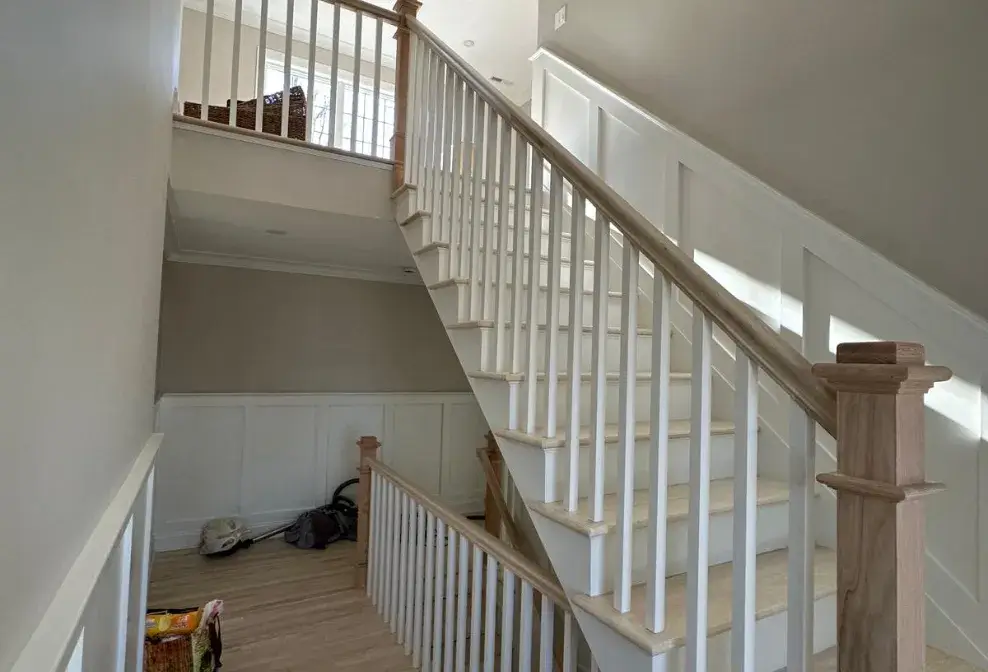 Interior wooden staircase with custom handrail and white balusters by Jorge Carpentry & Tile Services