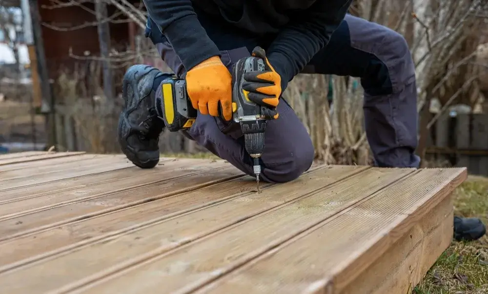 Carpenter using power drill on a wooden outdoor deck