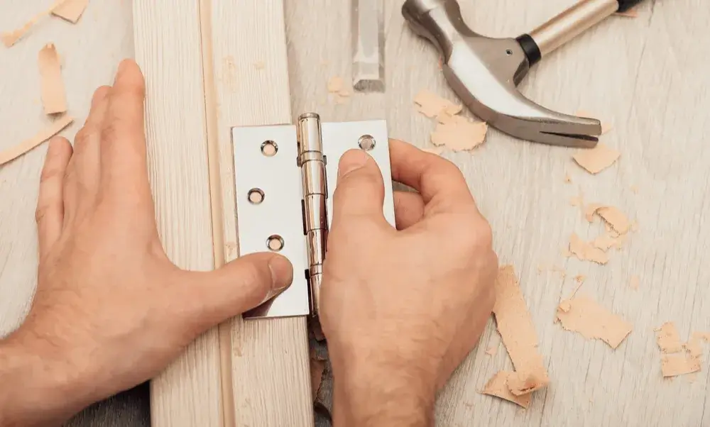 Carpenter aligning door hinge for new door installation