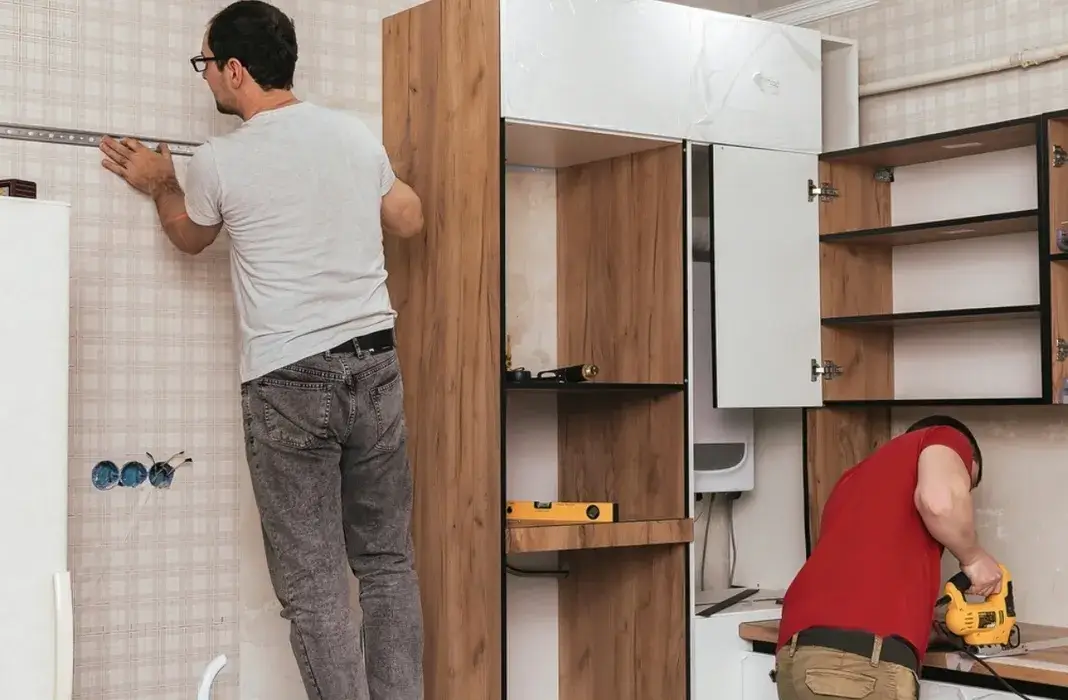 Carpenters installing custom kitchen cabinetry during renovation