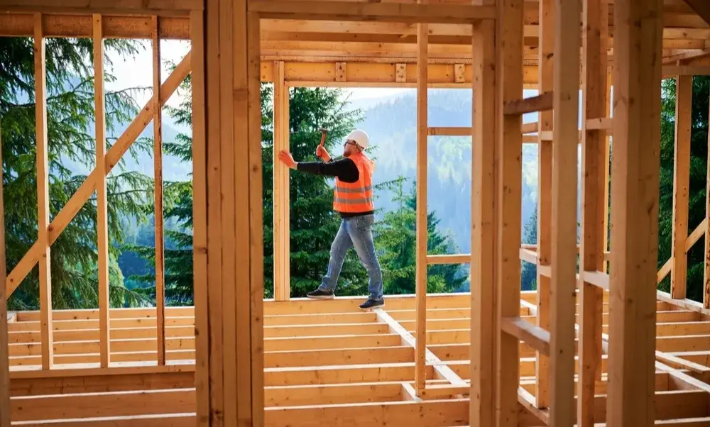 Construction worker walking on a wooden house frame