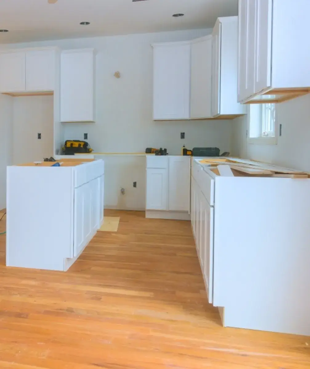 Custom white kitchen cabinets being installed on hardwood flooring